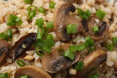 Photo of Delicious pearl barley with onion and mushrooms as background, closeup