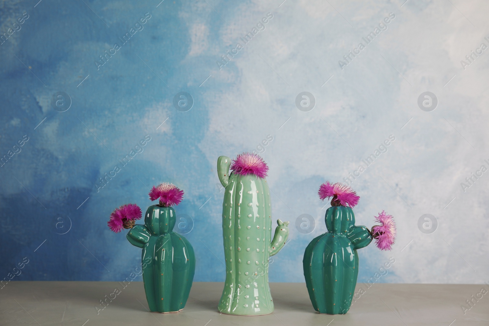 Photo of Trendy cactus shaped ceramic vases with flowers on table