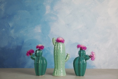 Photo of Trendy cactus shaped ceramic vases with flowers on table