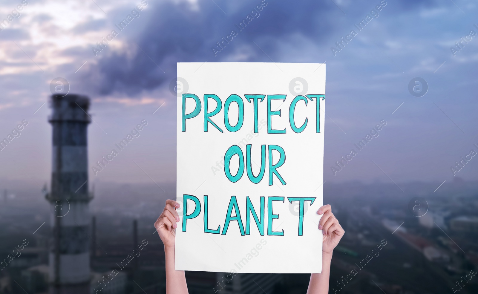 Image of Protestor holding placard with text Protect Our Planet and blurred view of industrial factory on background 