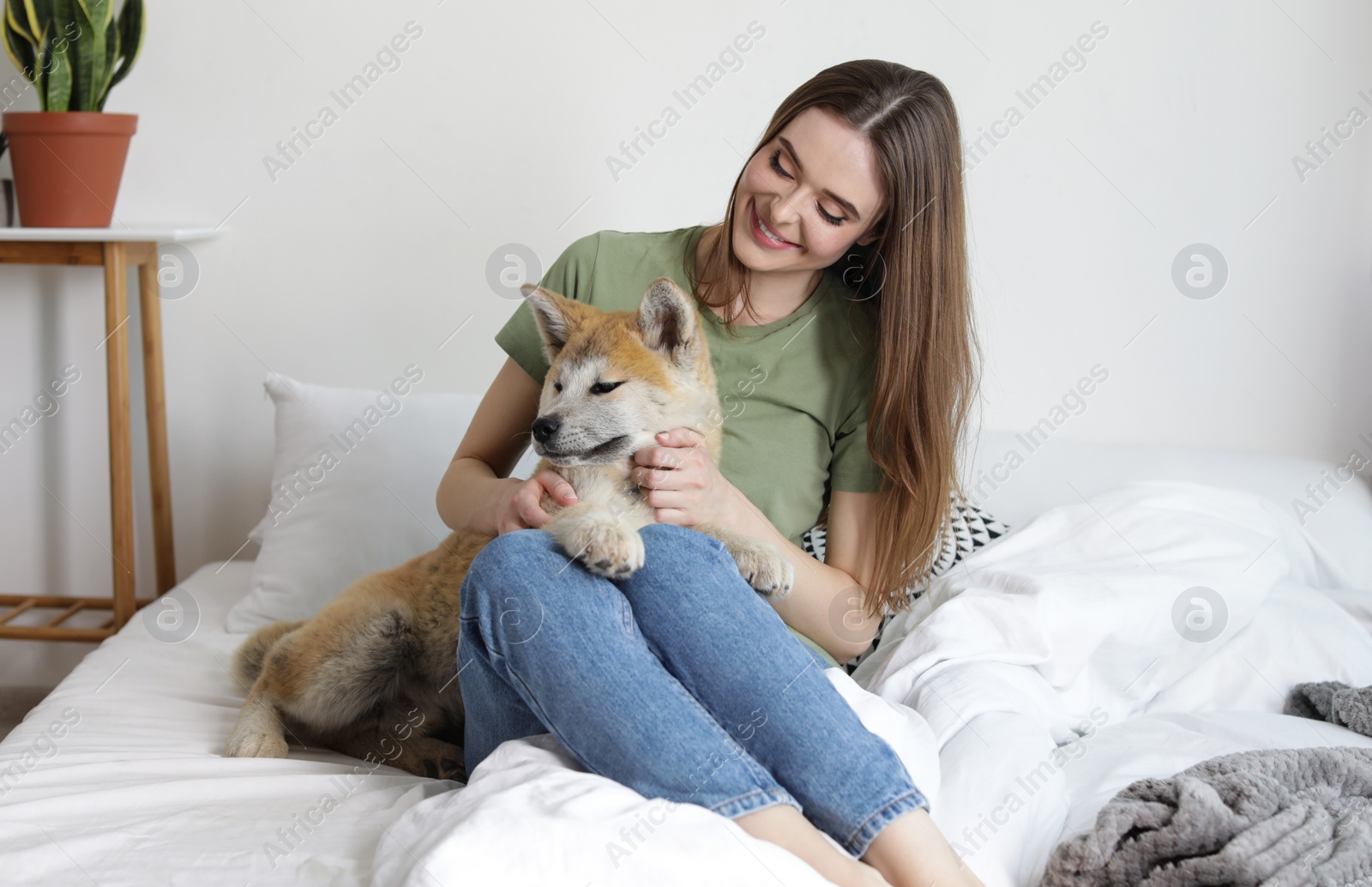 Image of Happy woman with her cute Akita Inu puppy at home