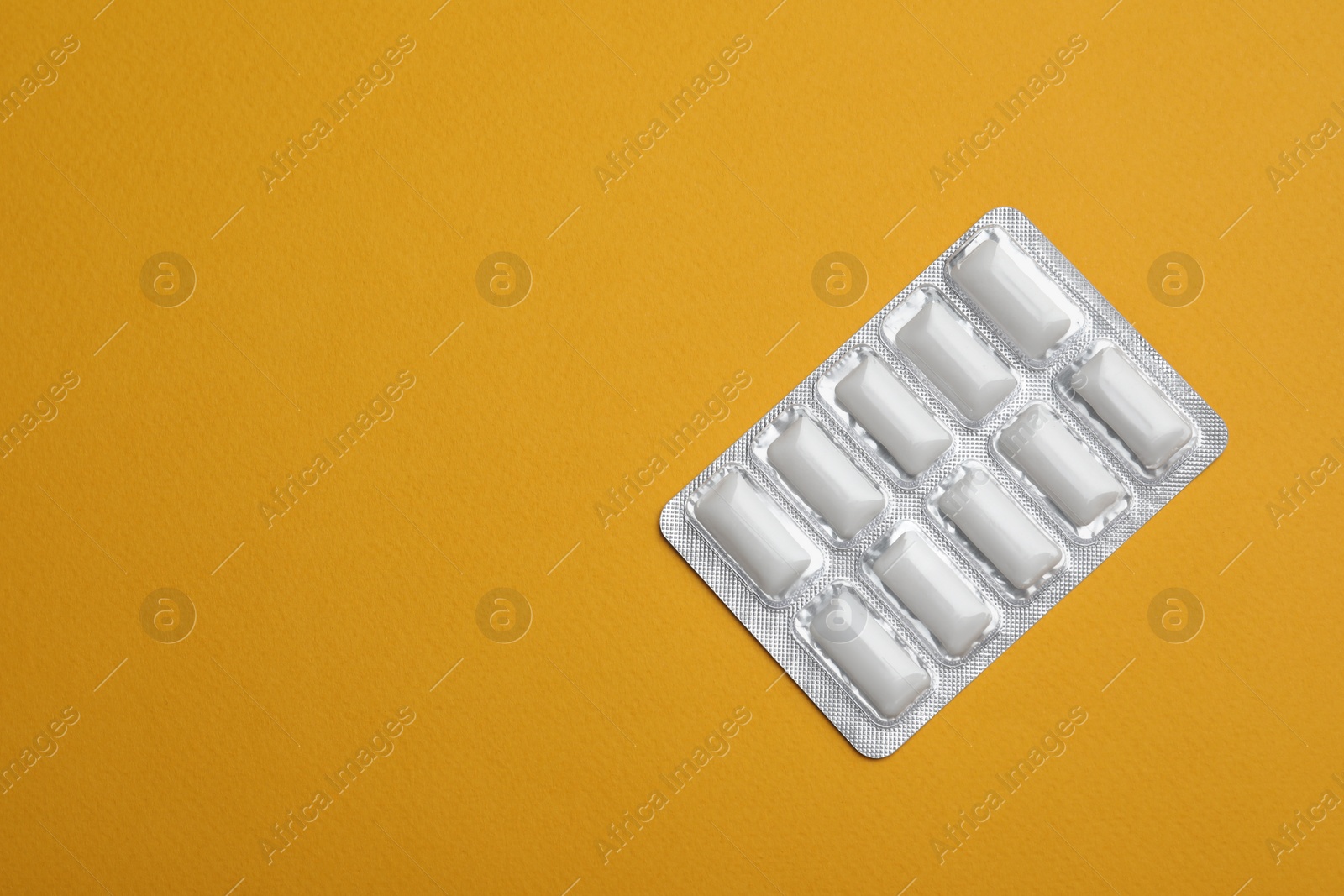 Photo of Blister of chewing gums on orange background, top view. Space for text