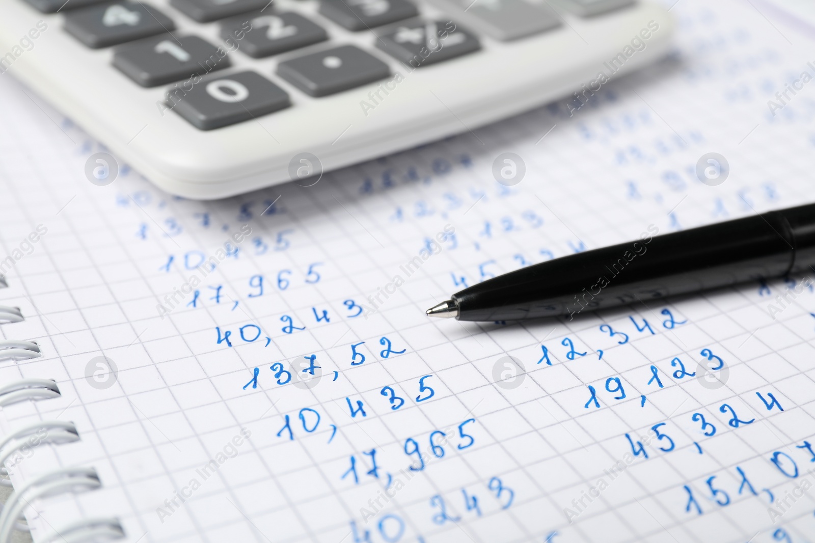 Photo of Calculator and pen on notebook with data, closeup view