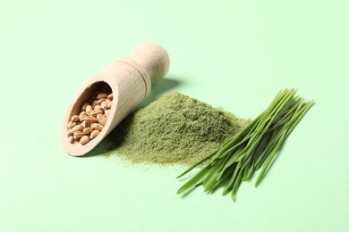 Pile of wheat grass powder, seeds in scoop and fresh sprouts on green table