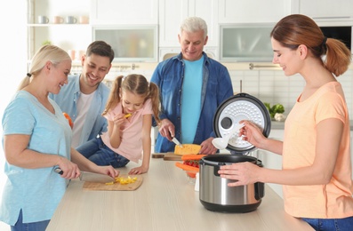 Happy family preparing food with modern multi cooker in kitchen