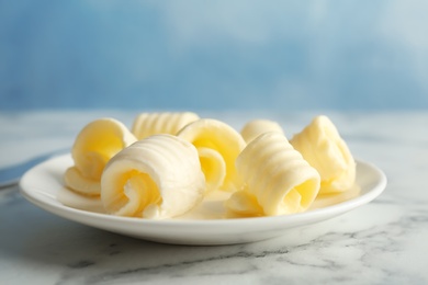 Plate with fresh butter curls on table