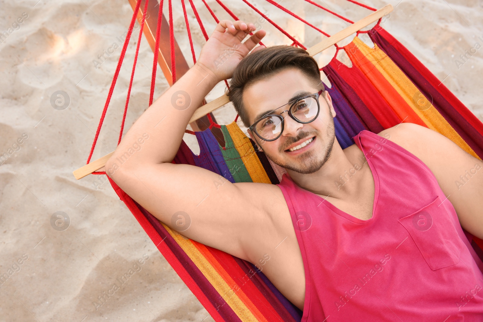 Photo of Young man resting in colorful hammock at seaside