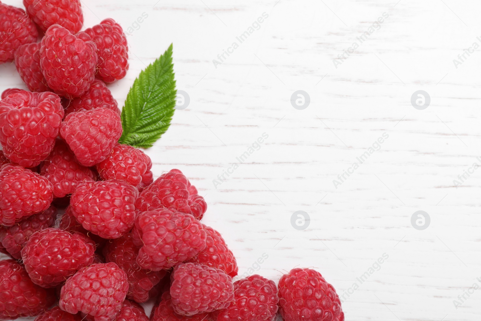 Photo of Delicious fresh ripe raspberries on white wooden table, top view. Space for text