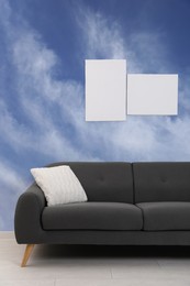 Image of Pattern of blue sky with clouds on wallpaper. Beautiful interior with sofa near wall
