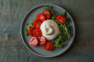 Photo of Delicious burrata cheese with tomatoes and arugula on grey wooden table, top view