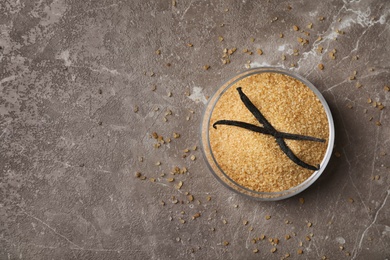 Photo of Bowl with brown vanilla sugar on color background, top view