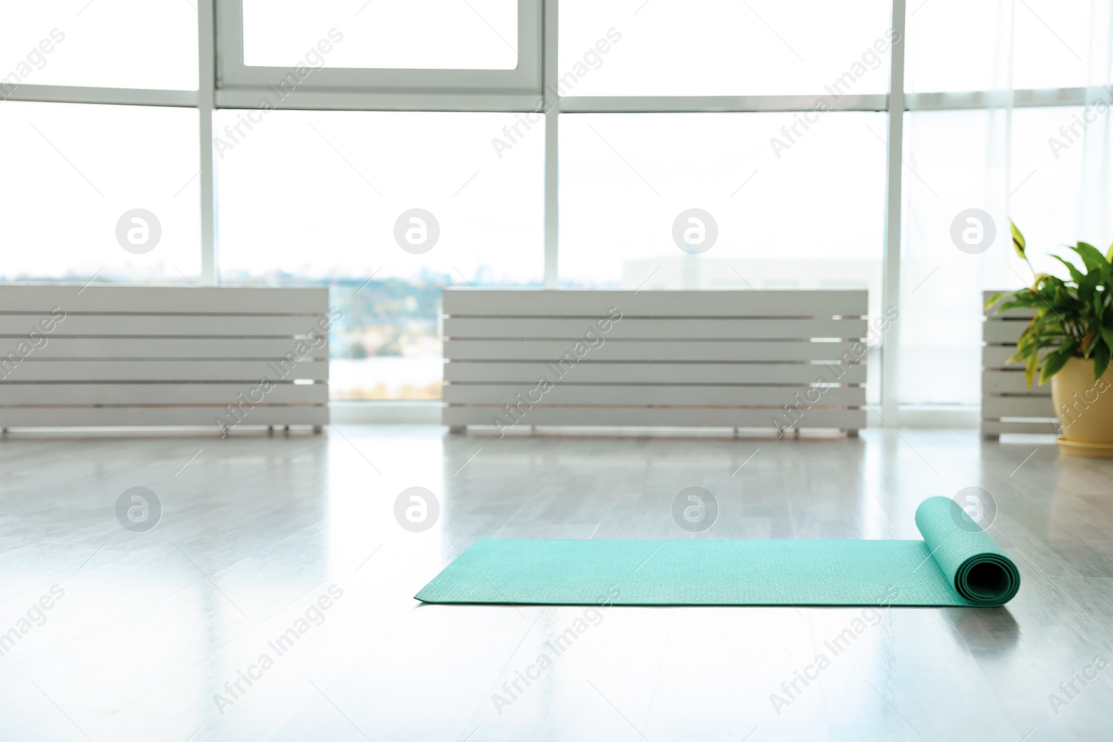 Photo of Unrolled light blue yoga mat on floor in room