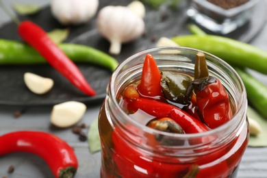 Photo of Glass jar of tasty pickled chili peppers, closeup