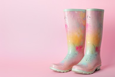 Photo of Pair of colorful rubber boots on pink background. Space for text