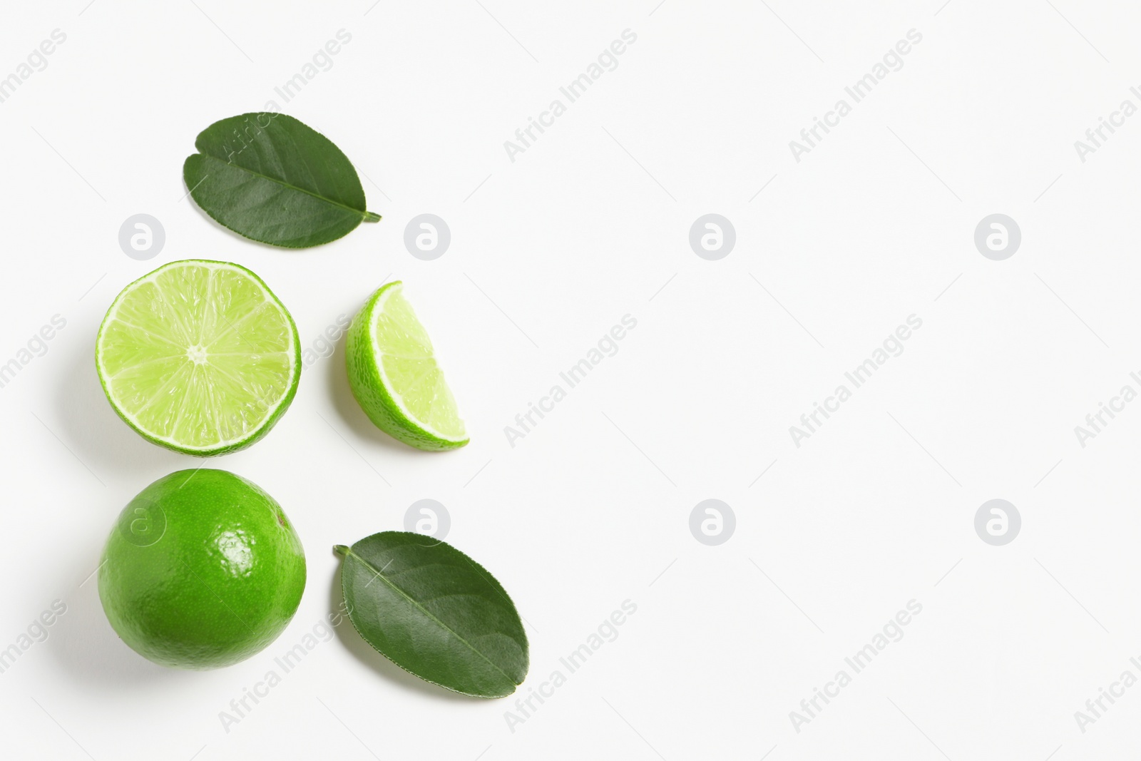 Photo of Fresh ripe limes and leaves on white background, flat lay. Space for text