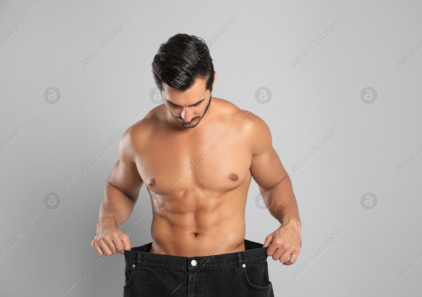 Photo of Young man with slim body in old big size jeans on grey background