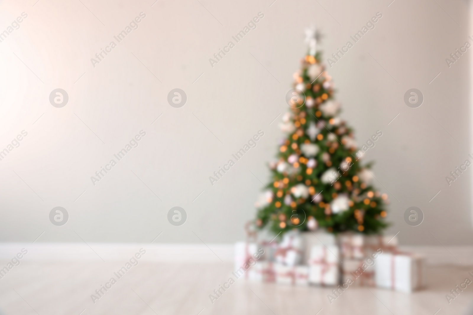 Photo of Beautiful decorated Christmas tree and gifts near light wall. Space for text