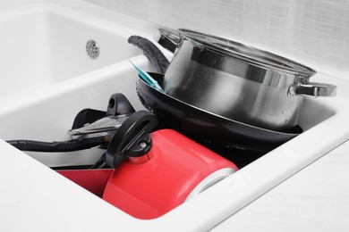 Messy pile of clean kitchenware in sink