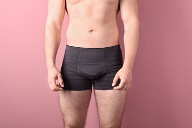 Attractive young man in underwear on color background