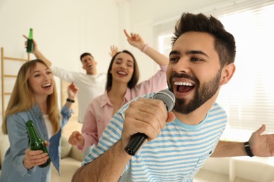 Young man singing karaoke with friends at home