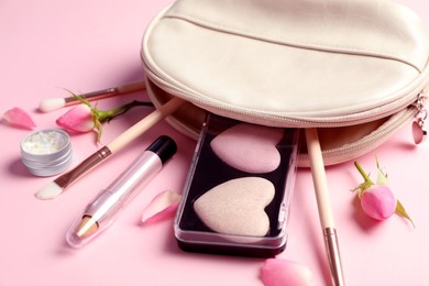 Photo of Setmakeup products with bag and roses on light pink background, closeup