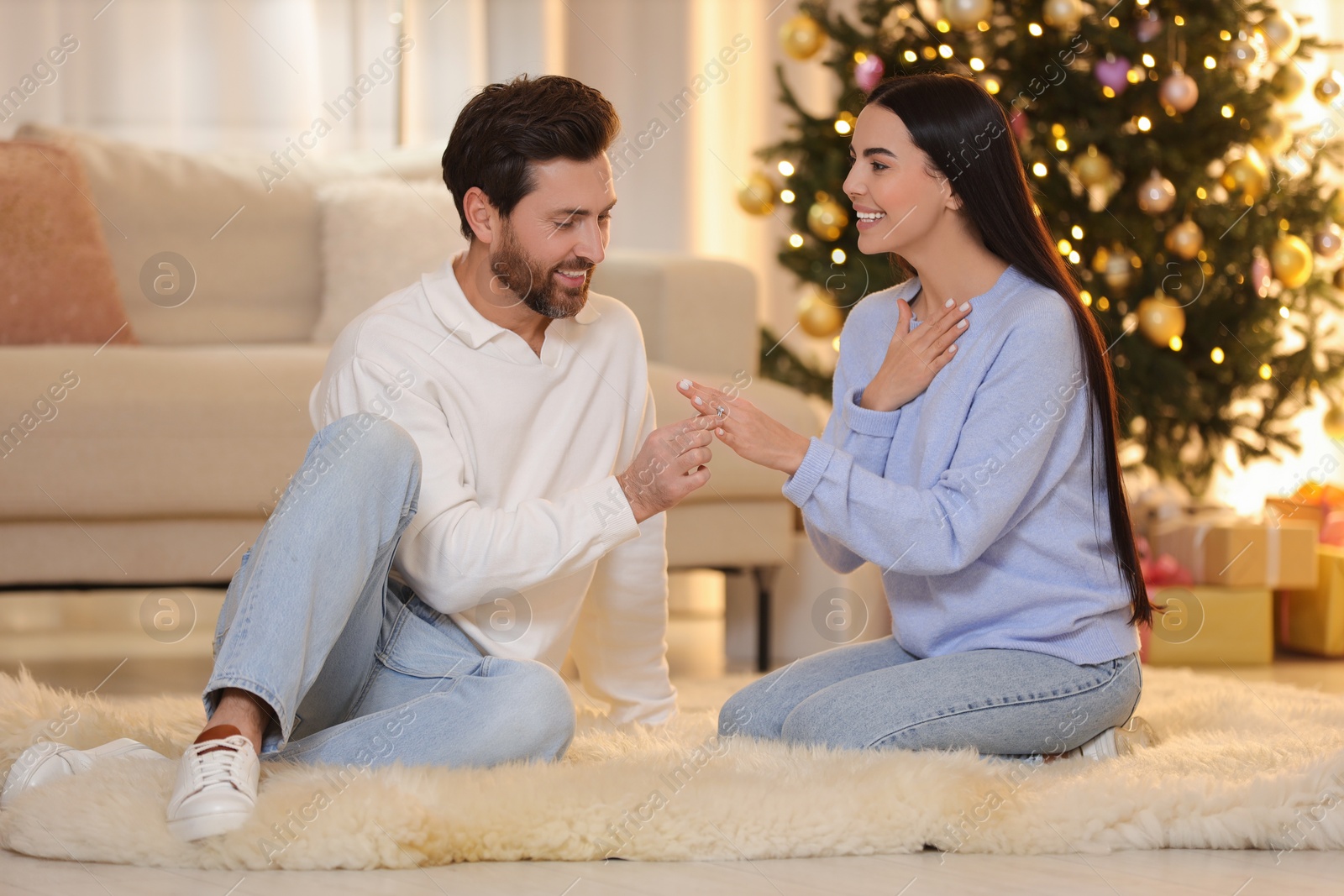 Photo of Making proposal. Man putting engagement ring on his girlfriend's finger at home on Christmas