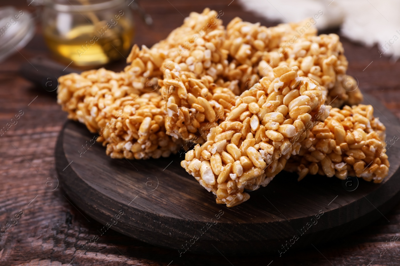 Photo of Board with puffed rice bars (kozinaki) on wooden table, closeup