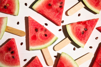 Photo of Slices of ripe watermelon on white wooden table, flat lay