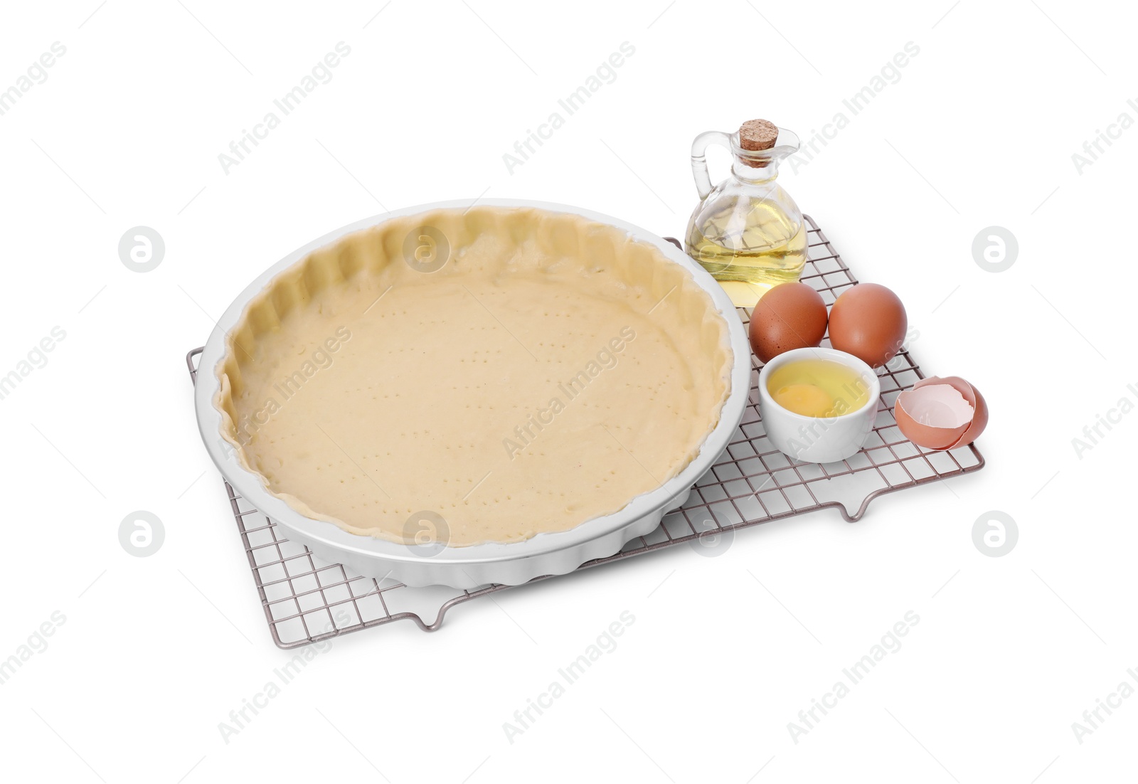 Photo of Quiche pan with fresh dough, oil and eggs isolated on white