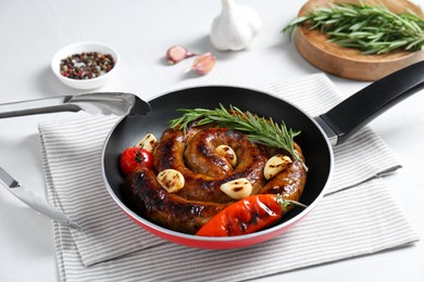 Photo of Delicious homemade sausage with garlic, tomato, rosemary and chili in frying pan on table, closeup