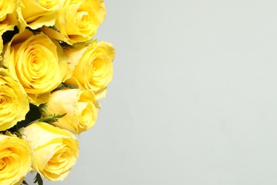 Beautiful bouquet of yellow roses on light grey background, closeup. Space for text