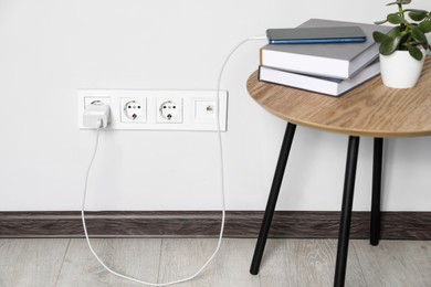 Photo of Modern smartphone charging from electric socket indoors