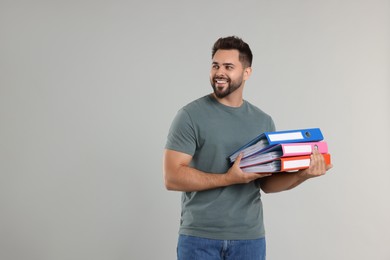 Happy man with folders on light gray background, space for text