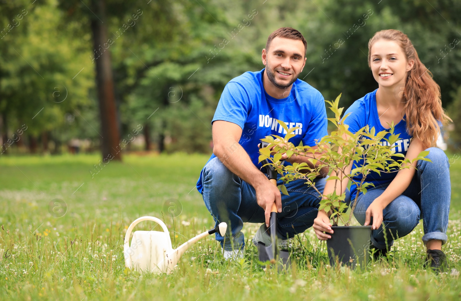 Photo of Young volunteers planting tree in green park. Charity work
