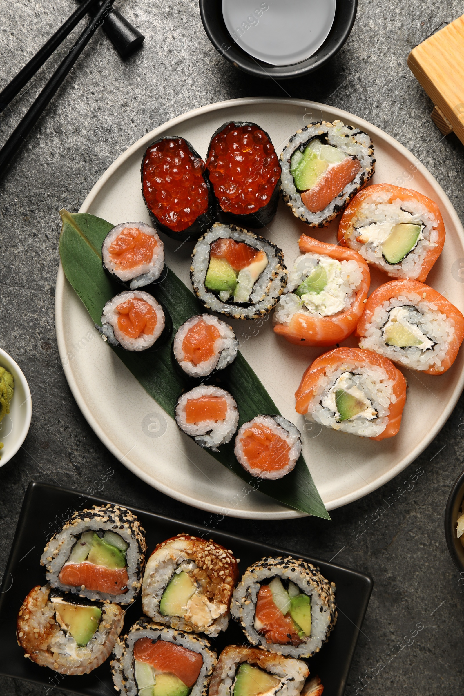 Photo of Flat lay composition with delicious sushi rolls on dark grey table