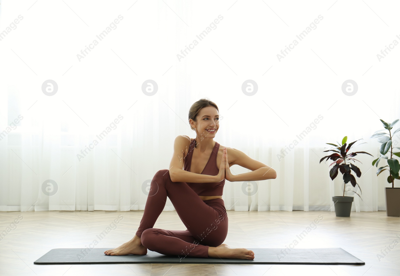 Photo of Young woman practicing half lord of fishes asana in yoga studio. Ardha Matsyendrasana pose