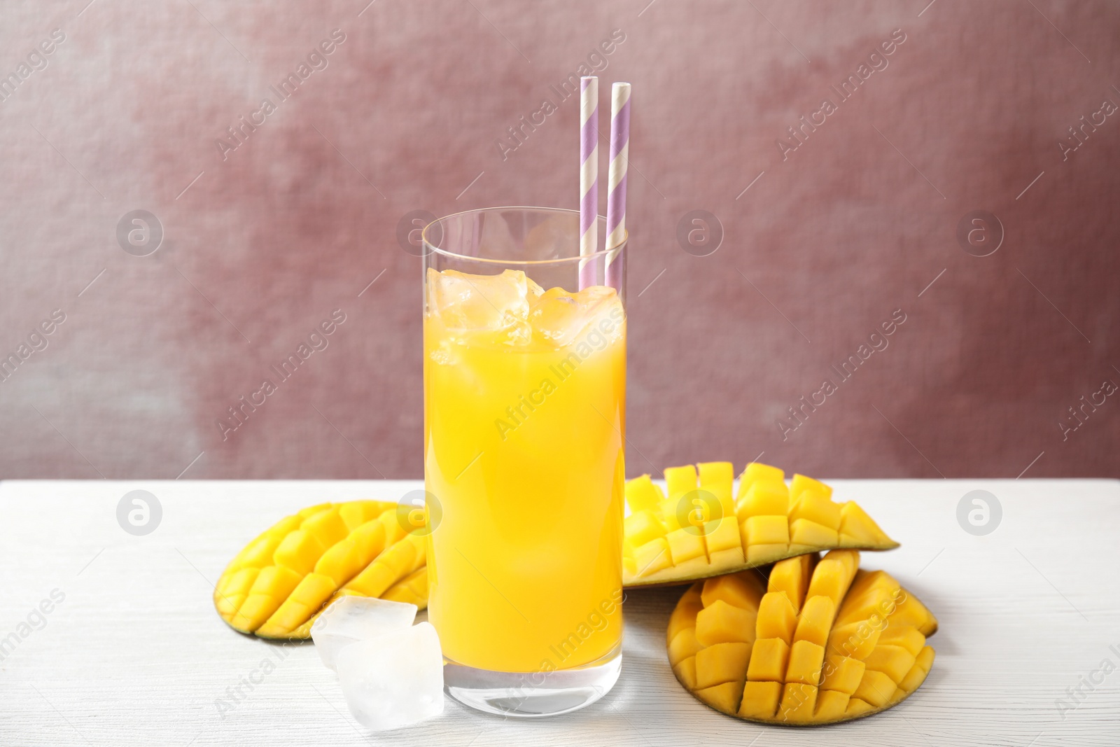 Photo of Fresh mango drink and fruits on table against color background