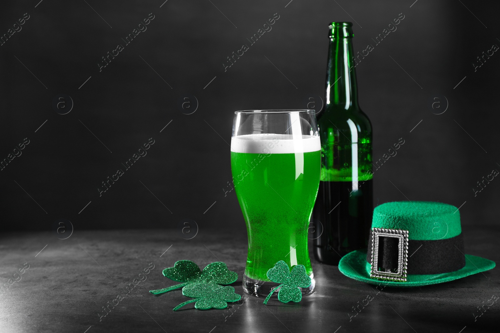 Photo of St. Patrick's day celebration. Green beer, leprechaun hat and decorative clover leaves on grey table. Space for text