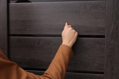 Woman knocking on door indoors, closeup view