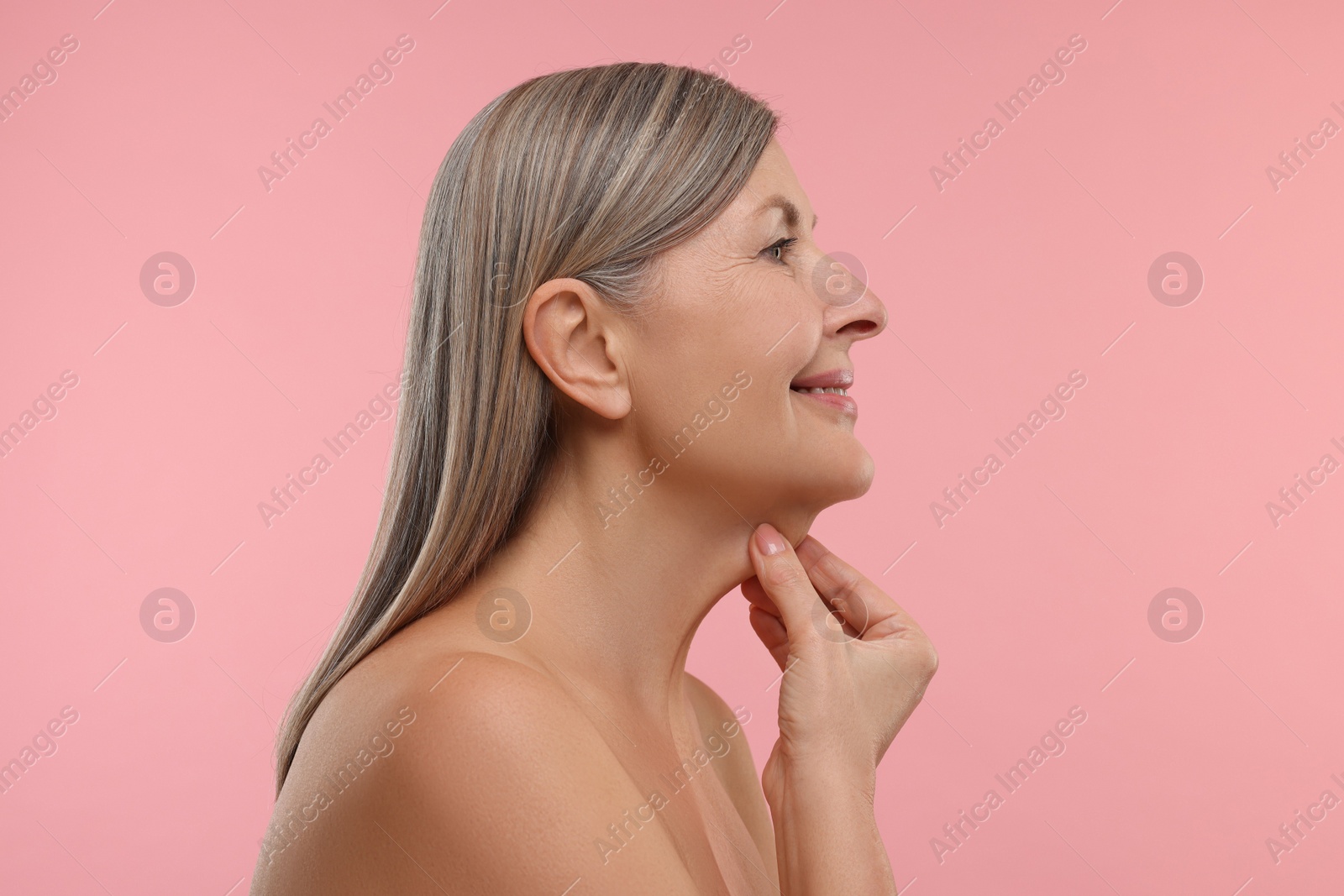 Photo of Mature woman touching her neck on pink background