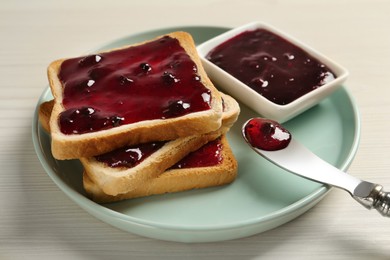 Photo of Delicious toasts with jam served on white wooden table, closeup