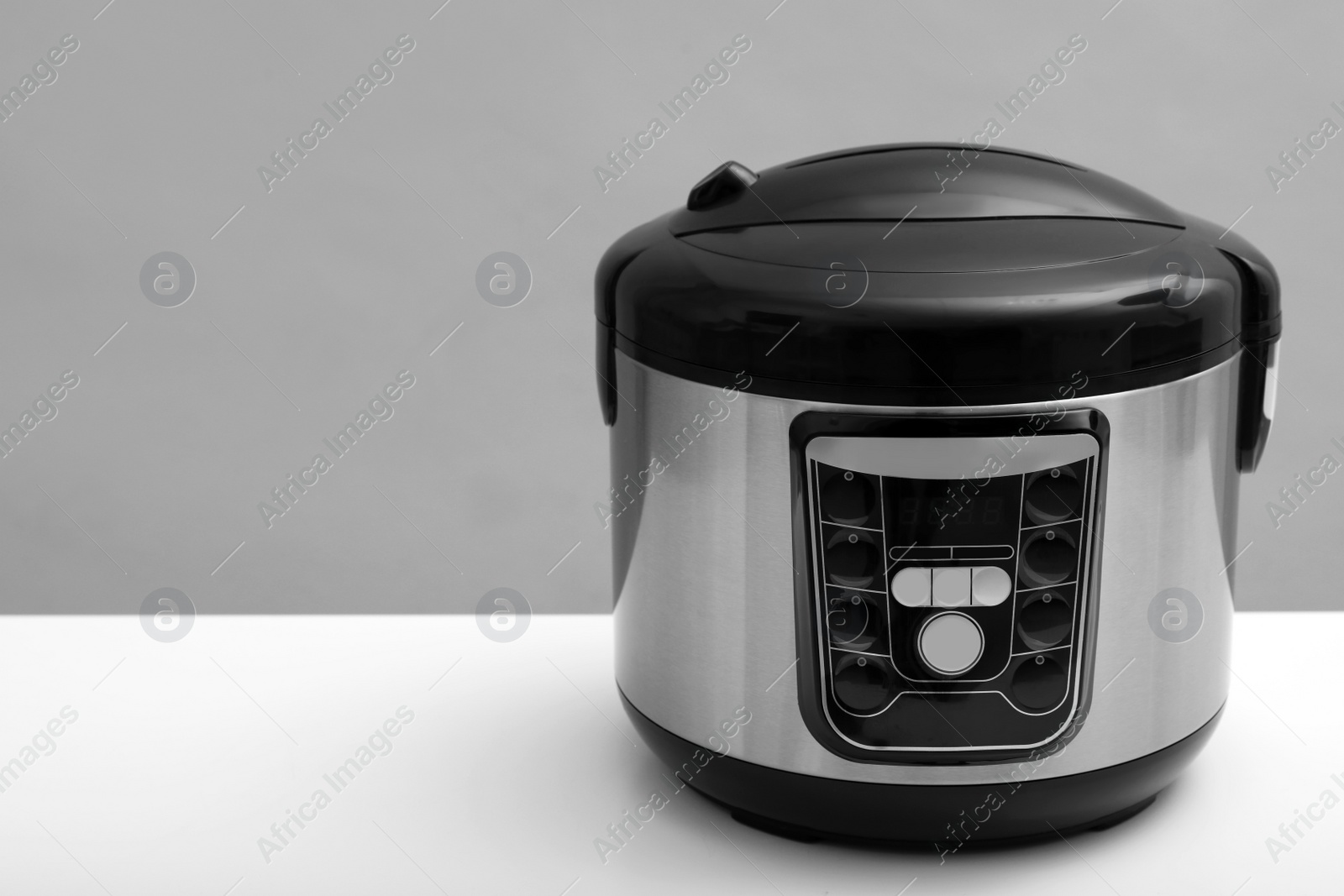 Photo of Modern electric multi cooker on table against grey background. Space for text