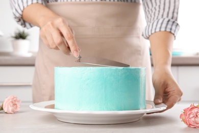 Photo of Woman making fresh delicious birthday cake in kitchen, closeup