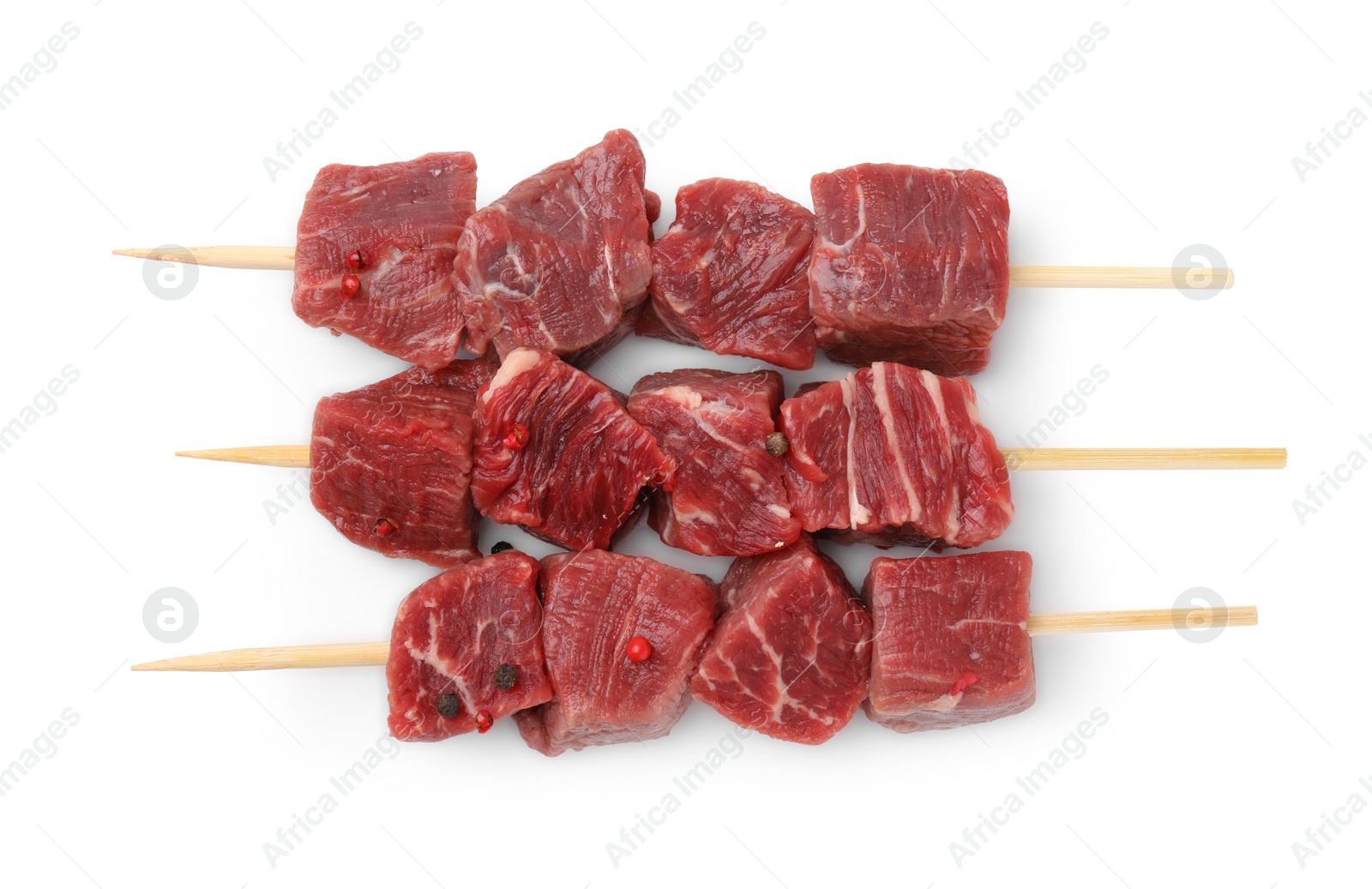 Photo of Wooden skewers with cut fresh beef meat isolated on white, top view