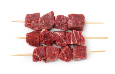 Photo of Wooden skewers with cut fresh beef meat isolated on white, top view