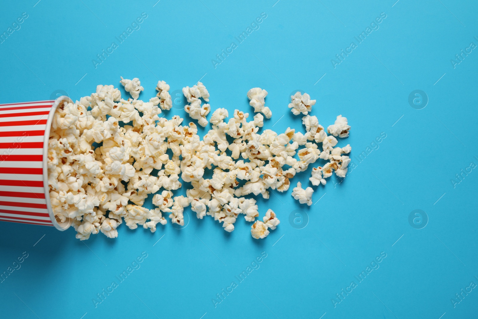 Photo of Delicious popcorn on light blue background, top view