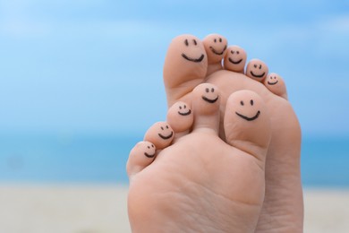 Photo of Woman with smiling faces drawn on toes outdoors, closeup of feet. Space for text