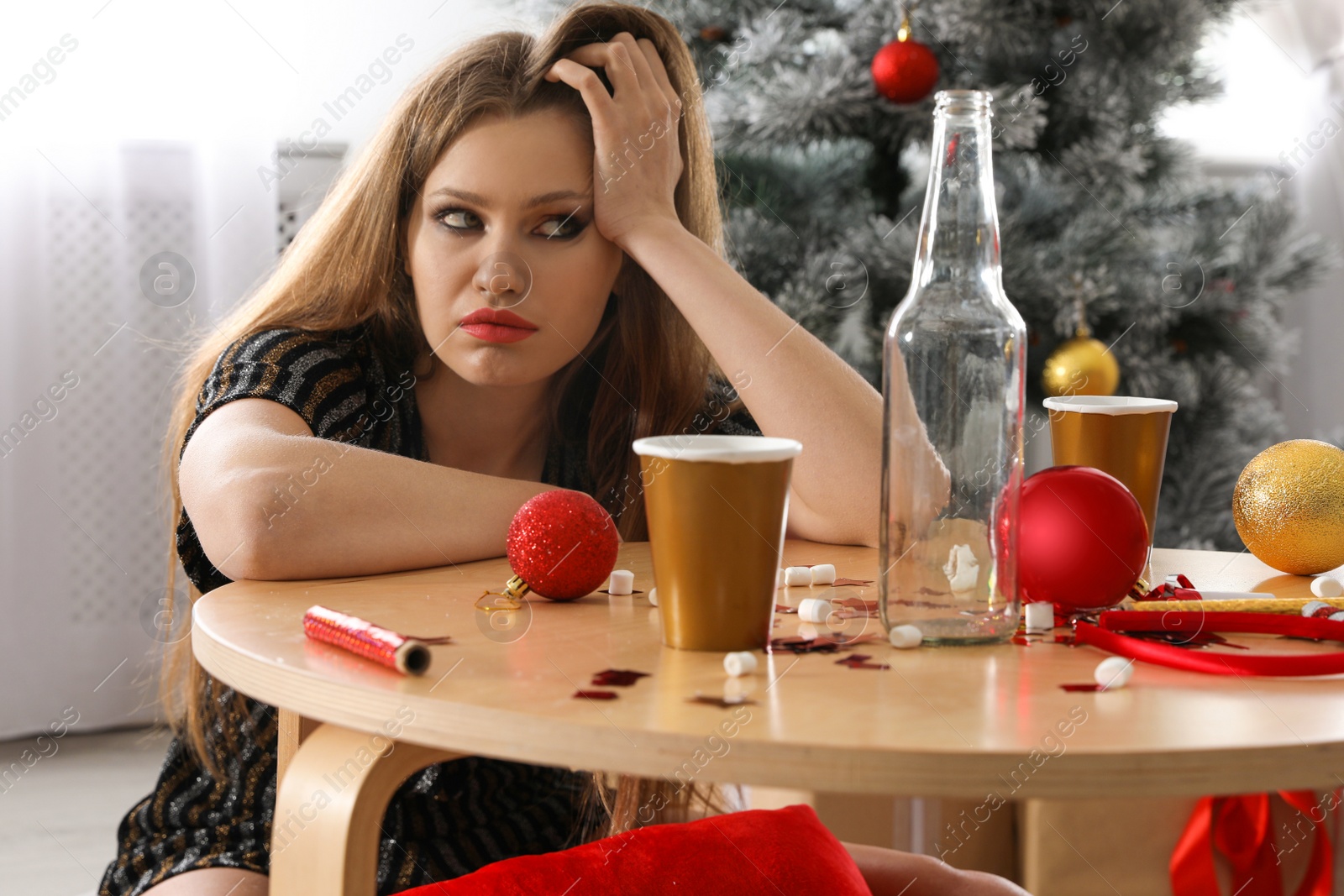 Photo of Young woman suffering from hangover at messy table after New Year party