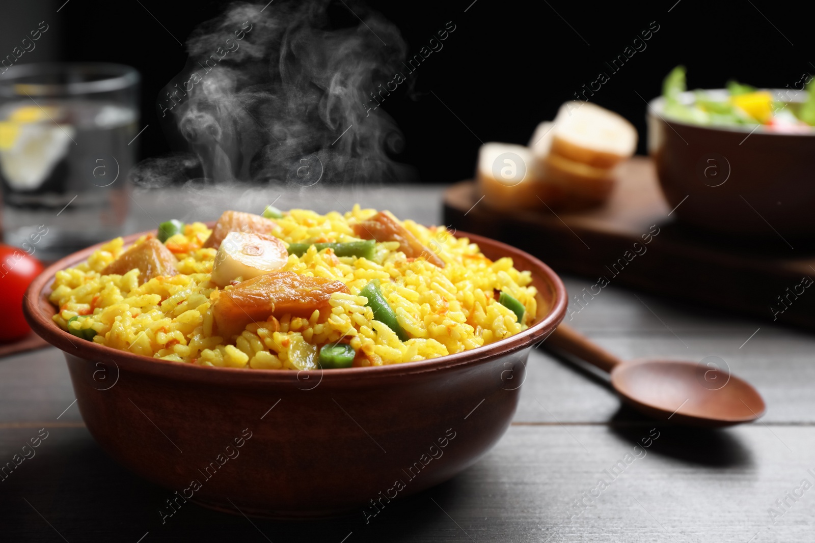 Image of Delicious pilaf with chicken meat on wooden table