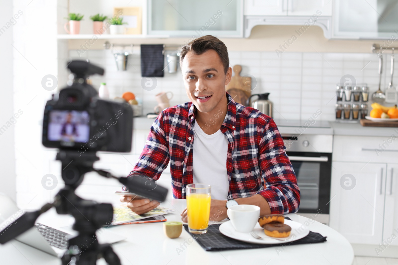 Photo of Food blogger recording video on camera in kitchen